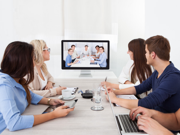 5 people in meeting looking a TV screen